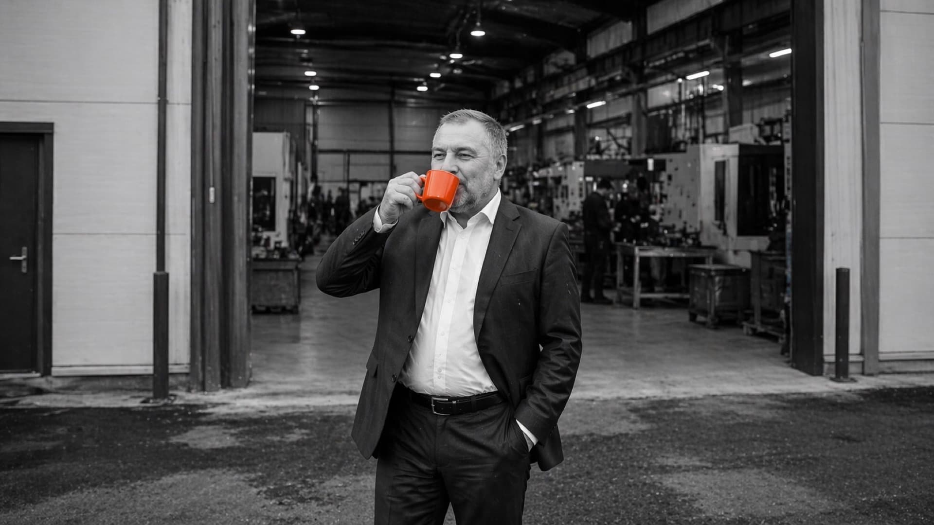 Unternehmer mit oranger Tasse in Produktionshalle Ostbayern